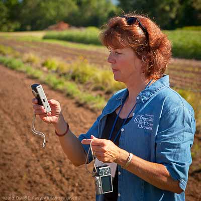 A woman in a field holding a digital camera