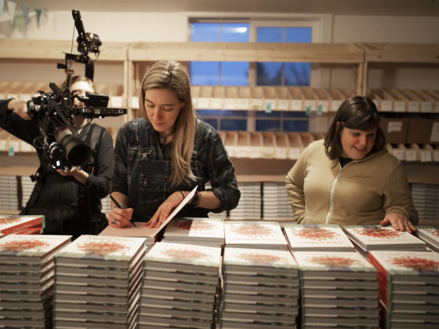 Erin Benzakein and Jill Jorgensen signing books while being filmed